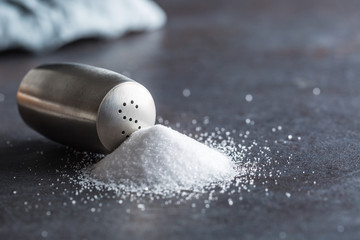 Spilled salt with staniless salt shaker - Closeup