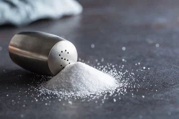 Fotobehang Spilled salt with staniless salt shaker - Closeup © weyo