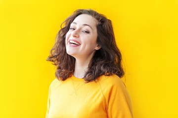Happy girl smiling. Beauty portrait young happy positive laughing brunette woman on yellow...