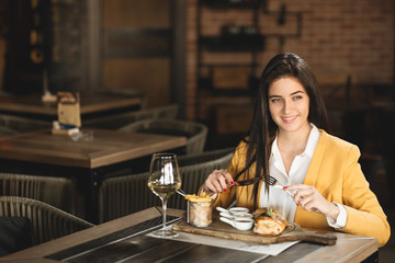 Businesswoman sitting in restaurant and eats after work