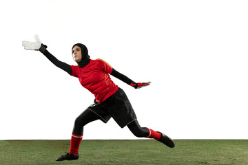 Fototapeta na wymiar Arabian female soccer or football player, goalkeeper on white studio background. Young woman catching ball, training, protecting goals in motion and action. Concept of sport, hobby, healthy lifestyle.