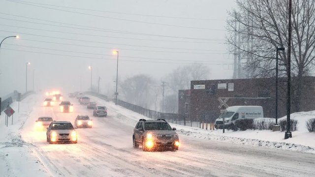 Zoom out of cars driving on winter road in heavy snow
