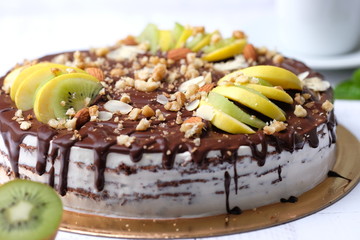 Tasty piece of chocolate cake with fruits, chocolate, apple, kiwi on cup of coffee americano, white background. Organic dessert sugarless. Healthy eating.