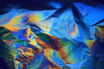 Holographic iridescent crumpled foil texture background