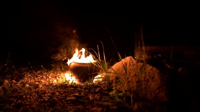 A young man lights two fire torches. Low key.