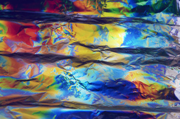 Holographic iridescent crumpled foil texture background