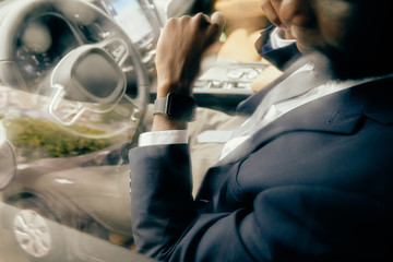 Close up of a man looking at his watch on driver's seat.