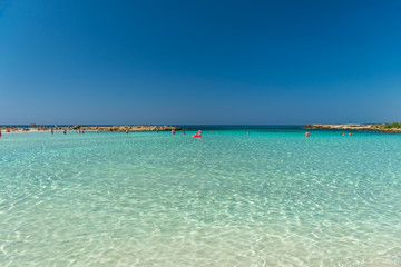Fototapeta na wymiar CYPRUS, NISSI BEACH - MAY 12/2018: Tourists relax and swim on one of the most popular beaches on the island.
