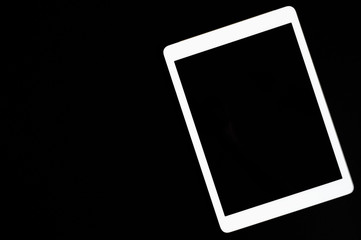 white tablet turned off on a black background. minimal black white concept. space for text