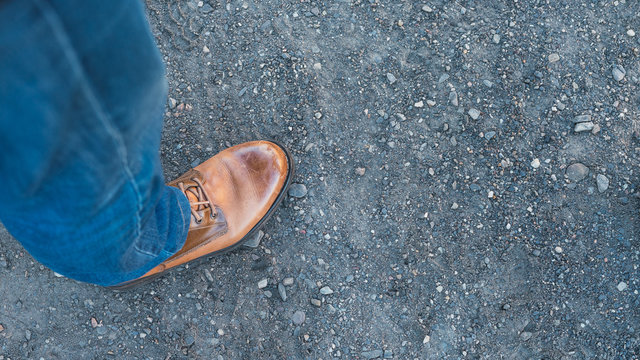 Bota de cuero con pantal&oacute;n vaquero  pisando un suelo arenoso