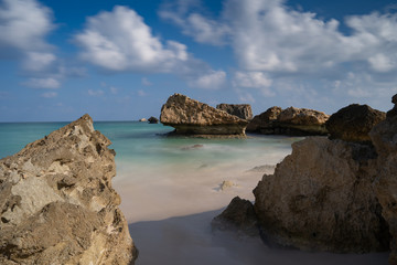 Fototapeta na wymiar longexposure, Fazayah Beach, Salalah Oman, Fantastic seascape, great outdoor scene of Beauty of nature concept background, blue sea, few clouds, light sandy beach, rocks in the water