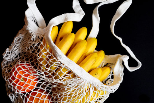 White String Mesh Bag Filled With Fruit Isolated On A Black Background