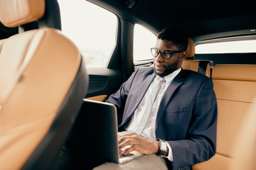 Businessman working on the laptop during a car ride.
