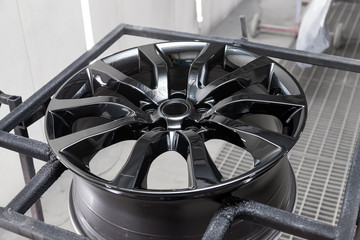 A black painted aluminum alloy wheel is mounted on a special frame during drying in a chamber in a...