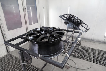 A Two black painted aluminum alloy wheel is mounted on a special frame during drying in a chamber...