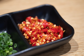 Seasoning of shabu, slice chili, green onion in a black bowl