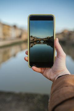 Young woman takes a picture of Ponte Vecchio in Florence with her smartphone - Detail of image taken with the phone - Point of view