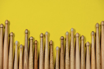 Close-up of many wooden drumsticks on a yellow background with copy space. Percussion instrument