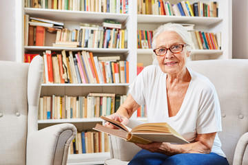 Neugierige Seniorin in der Bücherei liest ein Buch