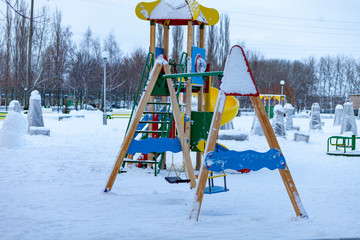 winter city park. Playground for children, slide, swing.