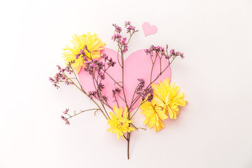 A large pink hear decorated with small pink flowers and yellow chrysanthemums on a white background