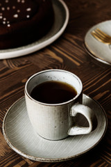 Moist Ginger Chocolate cake sprinkled with sea salt and cup of tea on wooden table. Selective focus.