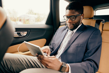 Naklejka na ściany i meble Man scrolling through the tablet screen during car ride.