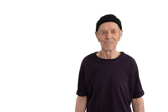 Old Happy Man In Black T-shirt And Hat, Stylish Senior In White Wireless Headphones Looking At The Camera Isolated Over White Background Copyspace For Your Text