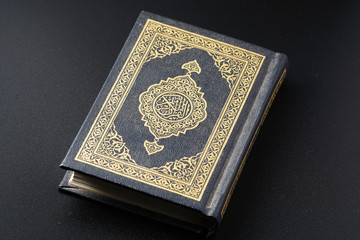 The Quran with rosary beads or “tasbih” and compass on wooden surface. Arabic characters means : Holy Quran, the Holy book of Islam. Islamic concept.