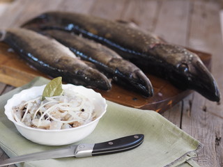 XE salad of freshly salted pike river fish on the background of pike river fish on a cutting board in the kitchen. We chop the pike on the fillet and prepare the XE salad.