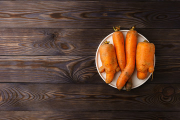 Ugly carrots on a white flat plate.