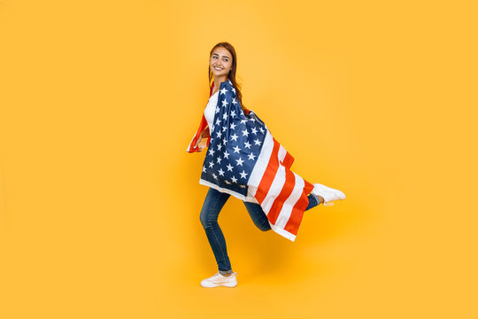 Young beautiful girl in a white t-shirt with the American flag, on a yellow background.