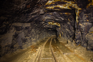 Old gold mine underground tunnel with rails
