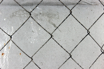 Rusty mesh netting against a dirty gray concrete wall