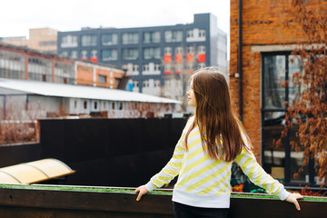beautiful teen girl long-haired teenager in yellow clothes on the background of the cityscape on the roof of the house