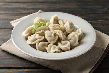 Towel and plate with dumplings on wooden background, close up