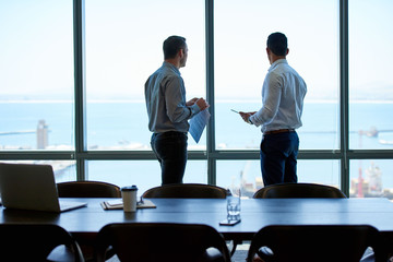 Business colleagues looking out over the ocean from a boardroom - Powered by Adobe