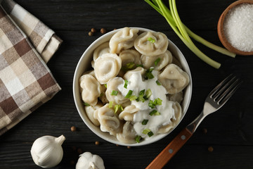 Bowl with dumplings, towel, fork and spices on wooden background, top view