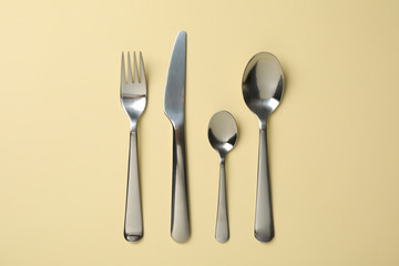 Cutlery on beige background, top view and space for text