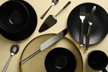 Tableware and cutlery on beige background, top view