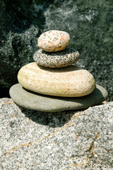 Fototapeta na wymiar Tower of four smooth river stones stacked on rock background, pink stone, close up