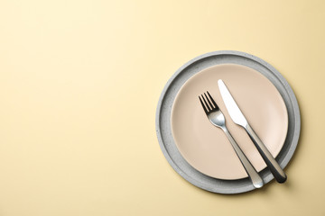 Tray with plate, fork and knife on beige background, top view