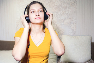 Cute young girl enjoying the music. girl sitting at living room and listening to music with headphones