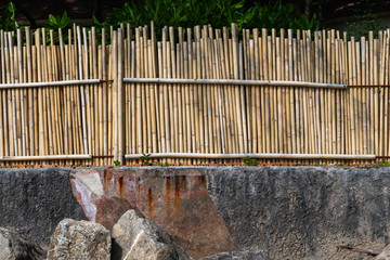 Dry bamboo fence with a rocks. Eco natural background concept.