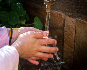 Young child washing hands with water