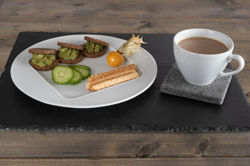 avocado on bread on a white plate with a cup of coffee.