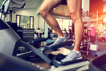 Man using elliptical trainer in fitness gym.