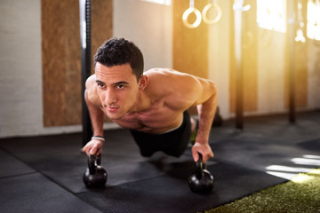 Fit man working out on a gym floor with weights