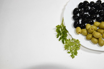 Favorite food. On a white background is a white plate with green and black olives.