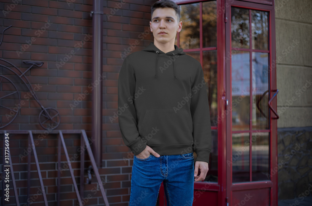 Wall mural Template black hoodie on a young guy, front view, presentation of clothes on the street. - Wall murals